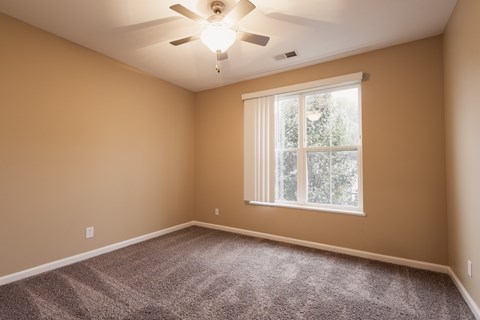 A room with a ceiling fan and a window.