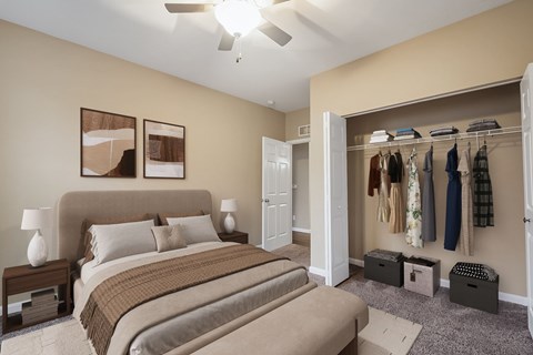 A bedroom with a large bed and a closet with clothes hanging.
