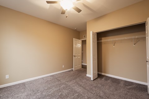 A room with a ceiling fan and a closet.