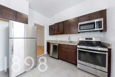 A kitchen with a refrigerator, oven, and microwave.