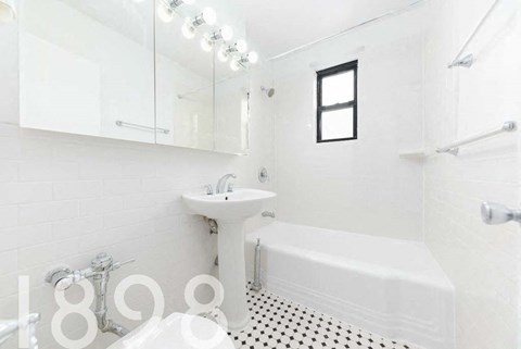 A white bathroom with a sink, mirror, and bathtub.