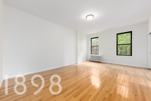 A room with wooden floors and two windows.
