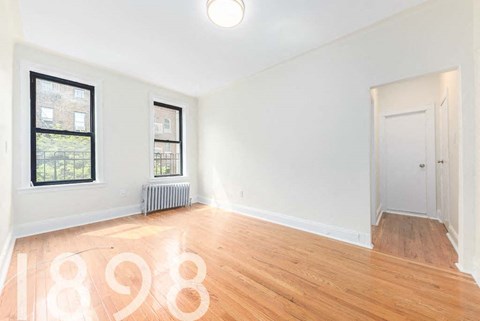 A room with wooden floors and a white wall with the number 1898 painted on it.