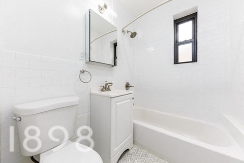 A white bathroom with a tub, toilet and sink.