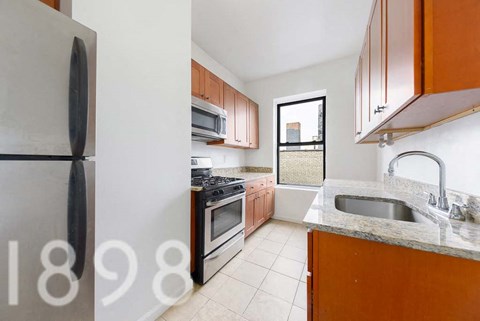 A kitchen with a refrigerator, sink, and stove.