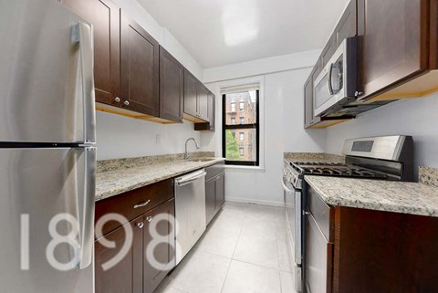 A kitchen with brown cabinets and a stainless steel refrigerator.