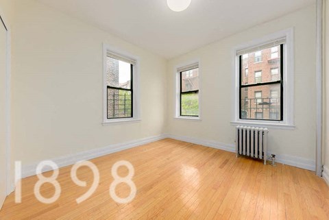 A room with wooden floors and two windows.