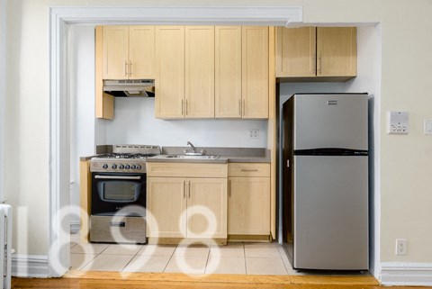 A kitchen with wooden cabinets and a refrigerator.