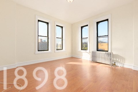 A room with wooden floors and three windows.