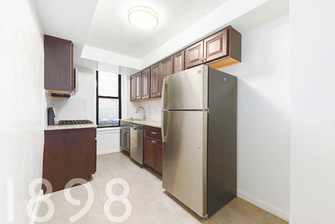 A kitchen with a refrigerator, sink, and cabinets.