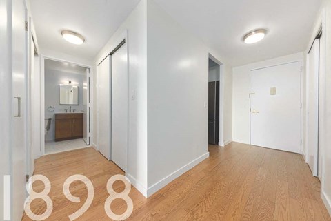 A hallway with a door on the right and a mirror on the left.