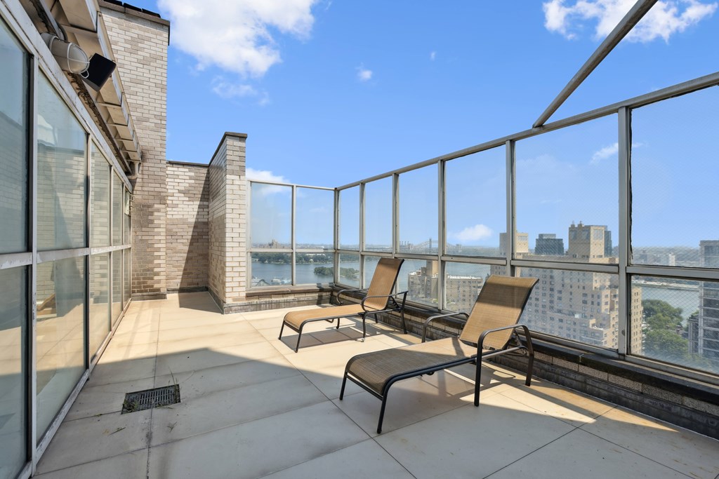 A balcony with chairs and a table overlooking a cityscape.