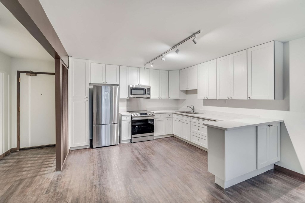 an empty kitchen with white cabinets and stainless steel appliances