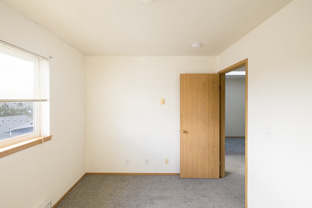 a bedroom with a door to a closet and a window