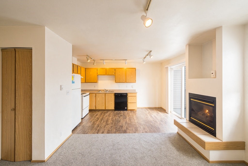 a living room with a fireplace and a kitchen with wooden cabinets