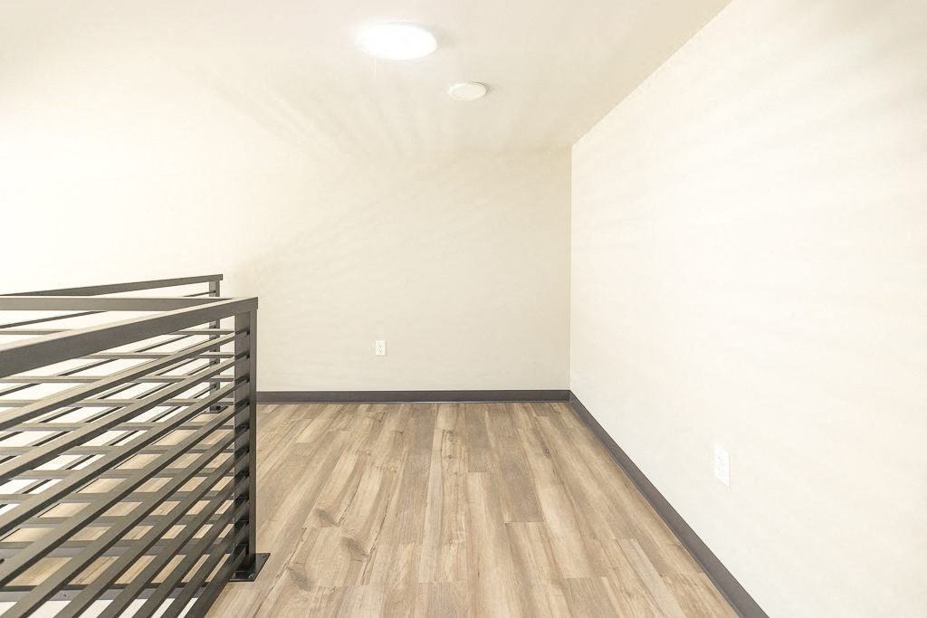 a bedroom with white walls and wood floors and a metal bed
