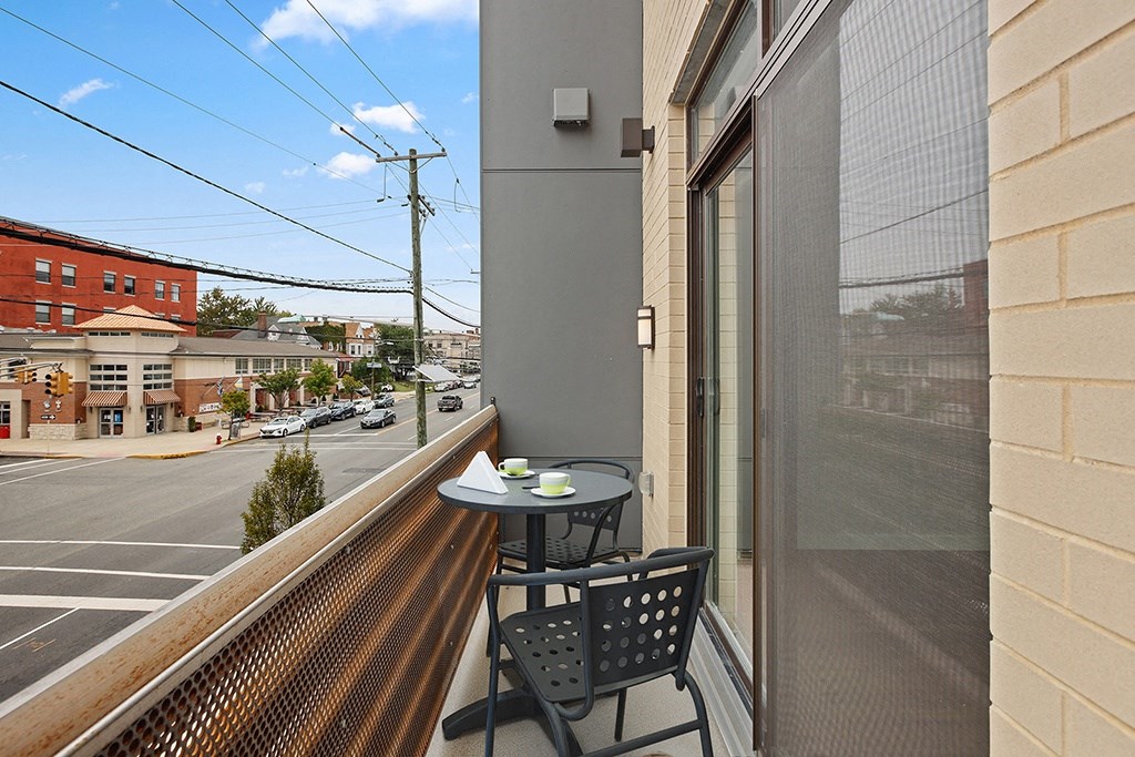 a balcony with a table and chairs and a window overlooking a street