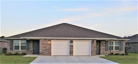a brick house with two white garage doors