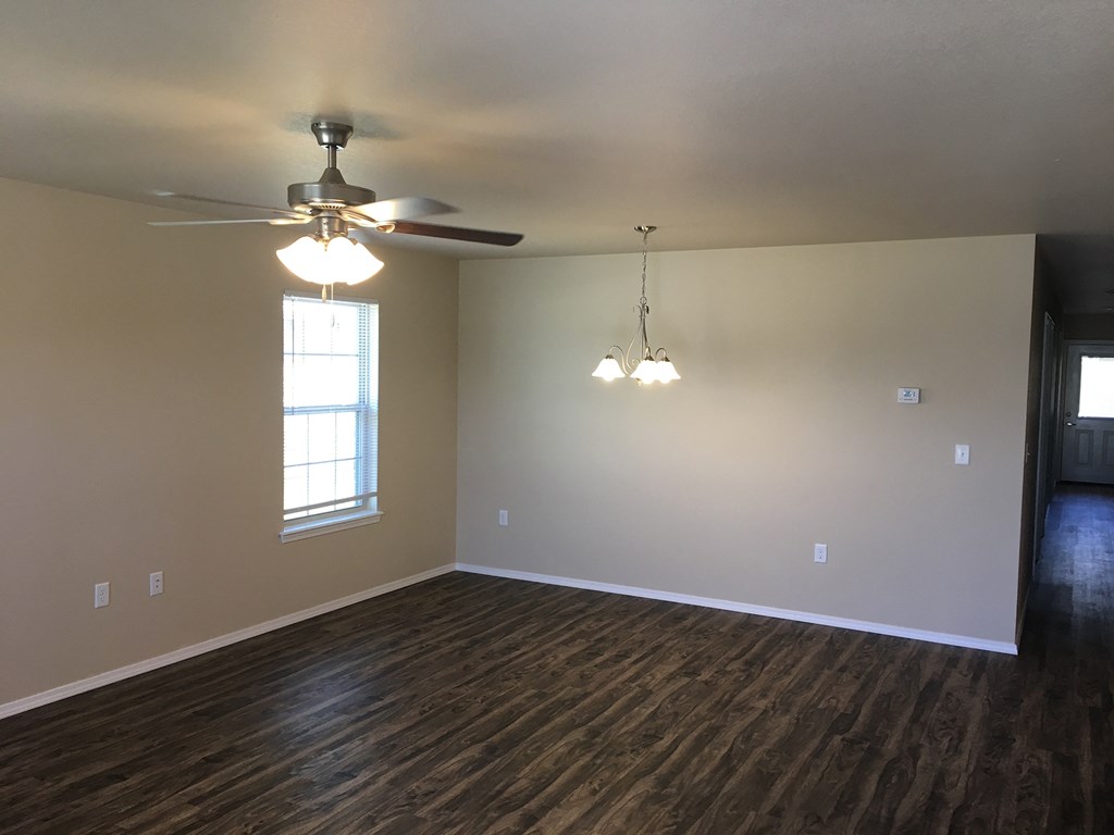 an empty living room with a ceiling fan and a window