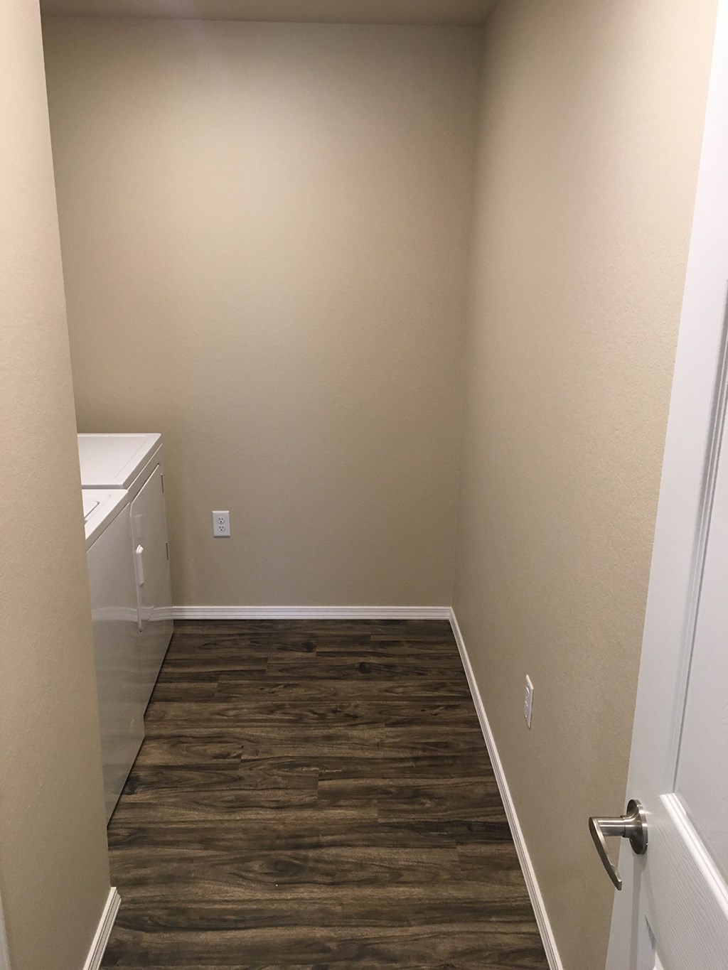 a small room with a wooden floor and a sink and a door