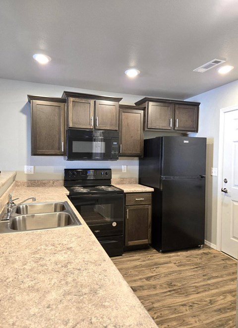 A kitchen with black appliances and wooden cabinets.
