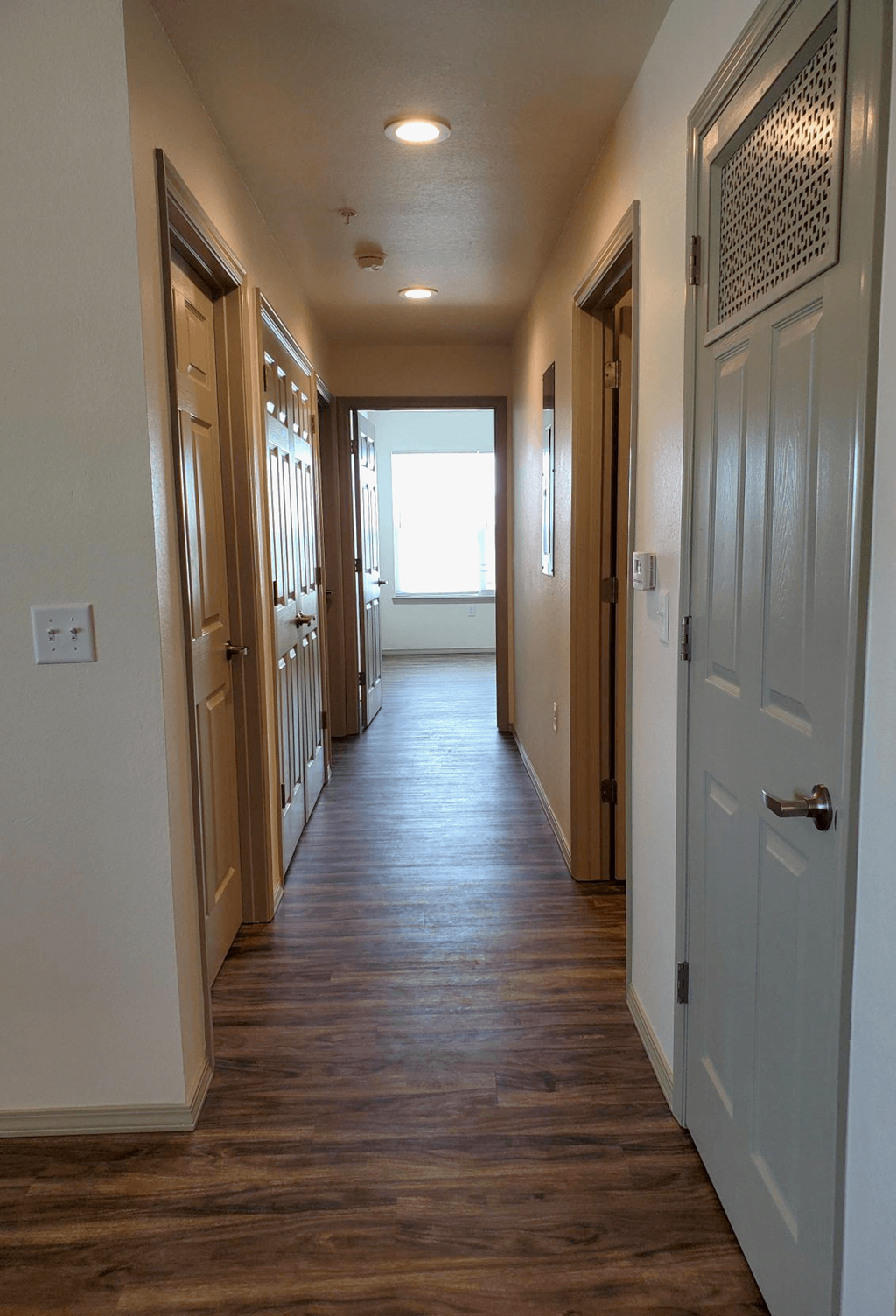 a hallway with a wood floor and white closets and doors