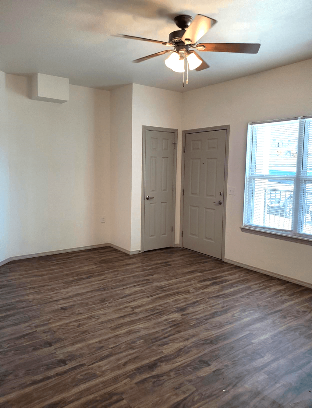 an empty living room with a ceiling fan and a window