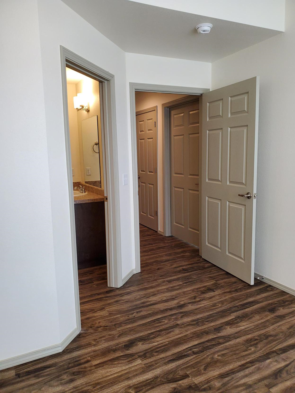 a room with a hallway with two doors and a bathroom