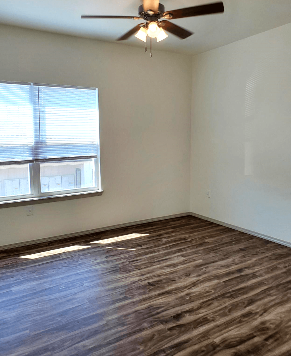 an empty living room with a ceiling fan and a window