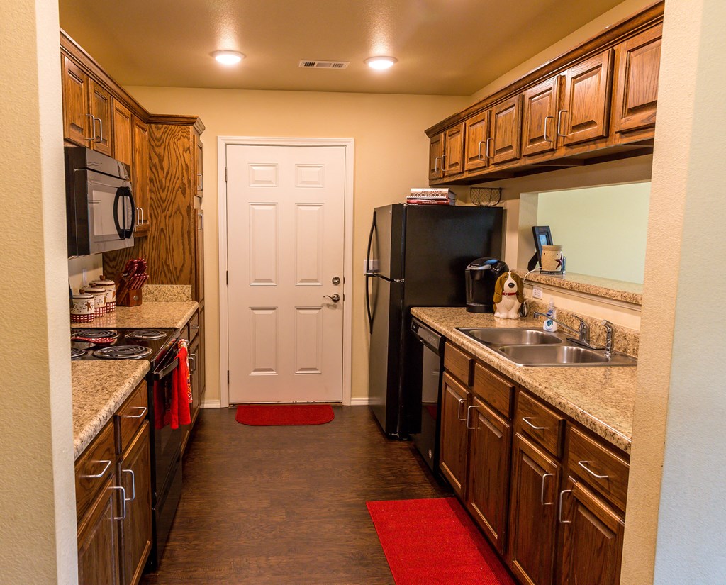 a kitchen with granite counter tops and wooden cabinets and a black refrigerator