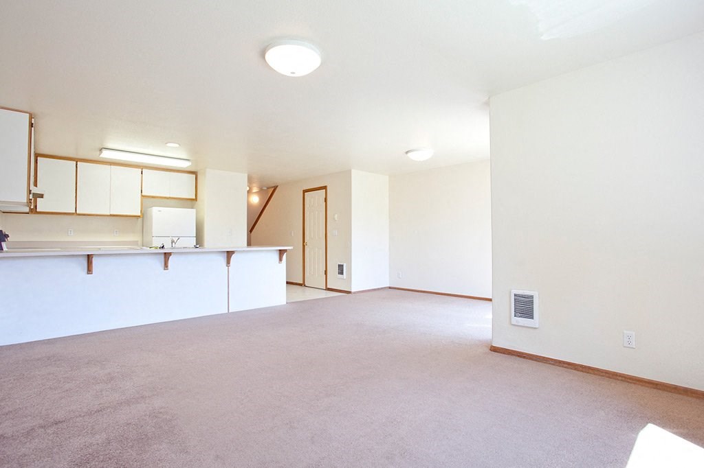 the living room and kitchen of an empty apartment