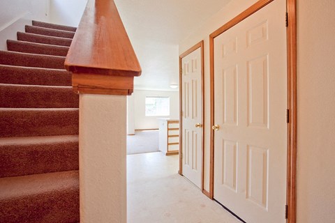the entryway of a house with a staircase and a white door