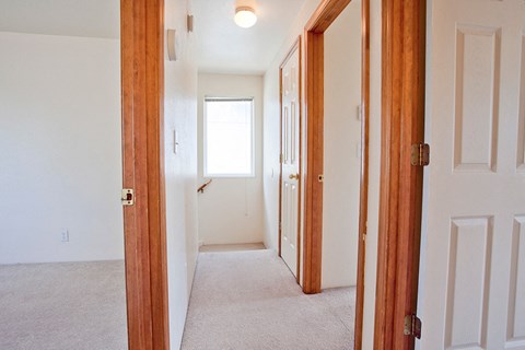 an empty hallway with two doors and a window in a house