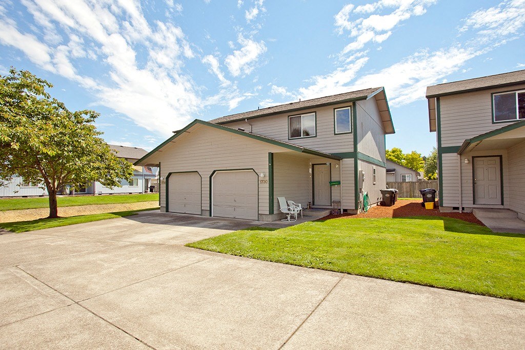 a driveway in front of a house with a lawn