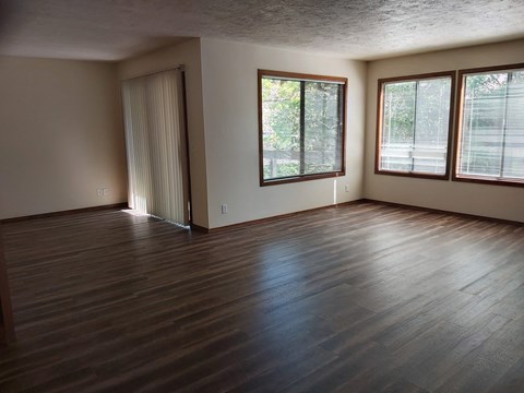 an empty living room with wood floors and windows