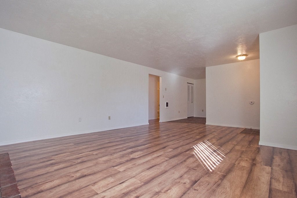 the spacious living room with hardwood floors and white walls