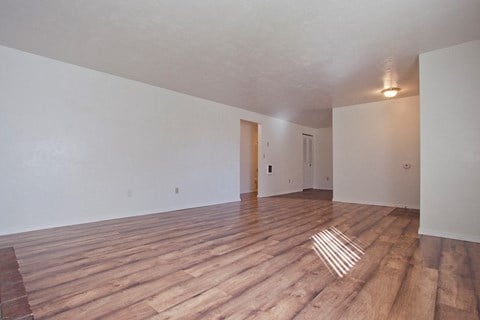 the spacious living room with hardwood floors and white walls