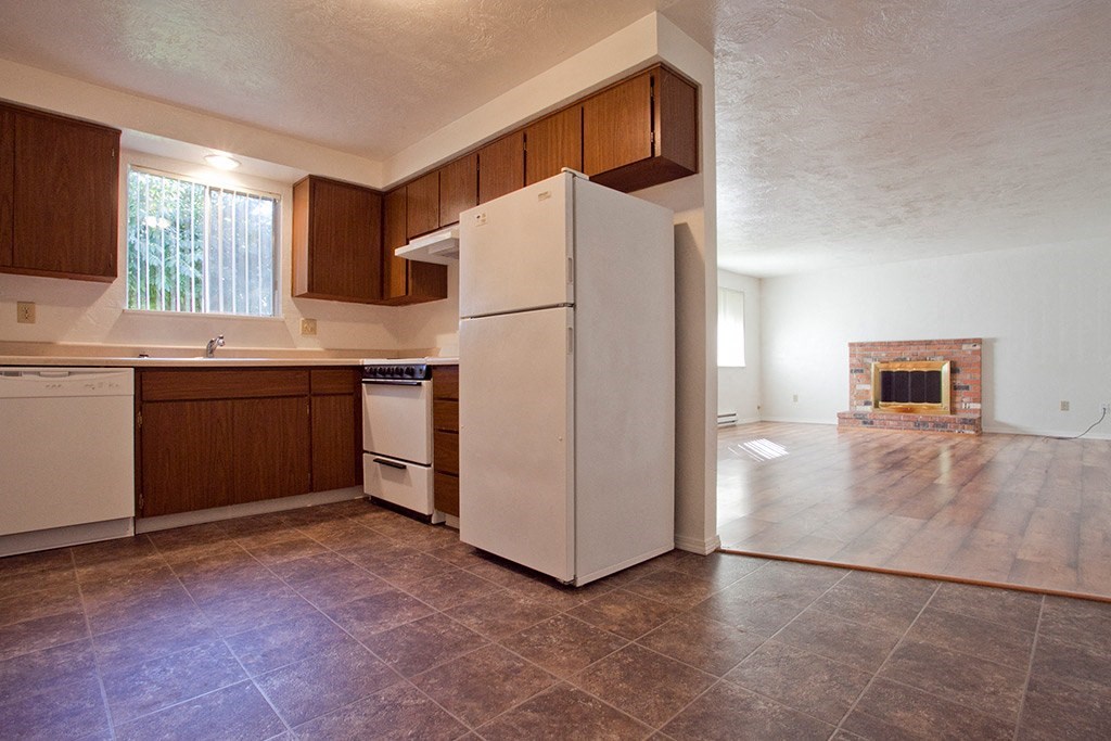 an empty kitchen with white appliances and a fireplace