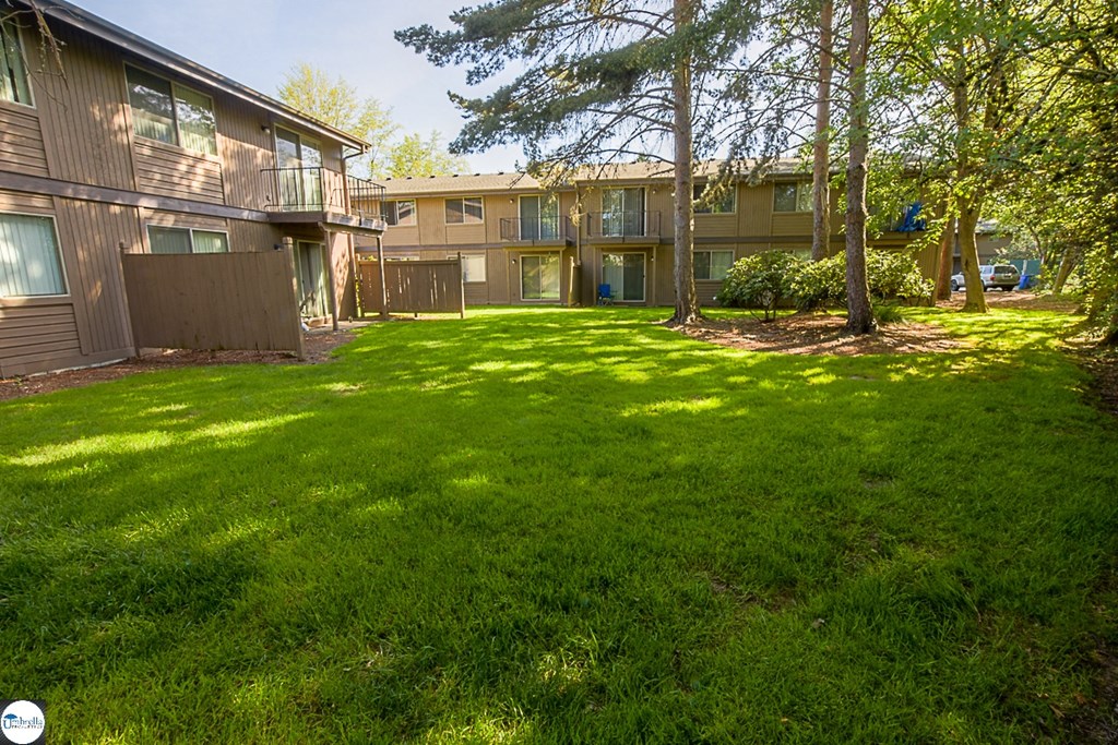 the backyard of an apartment building with green grass and trees