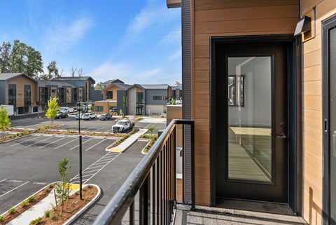 A view of a parking lot from a balcony with a building in the background.