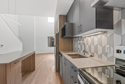 A modern kitchen with a white countertop and stainless steel appliances.