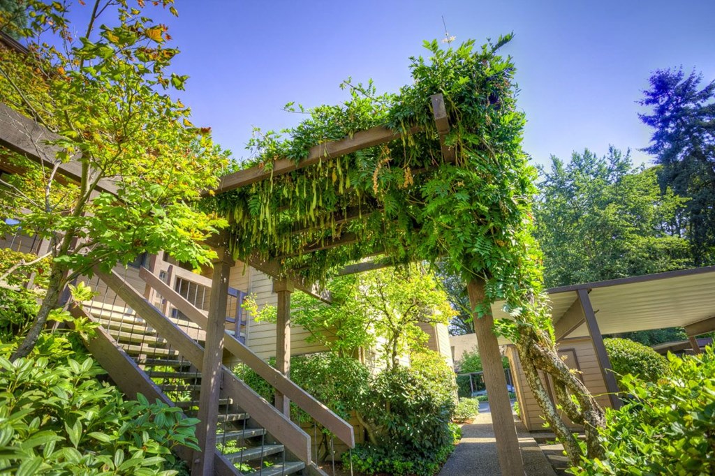 a covered walkway with stairs and plants on a building