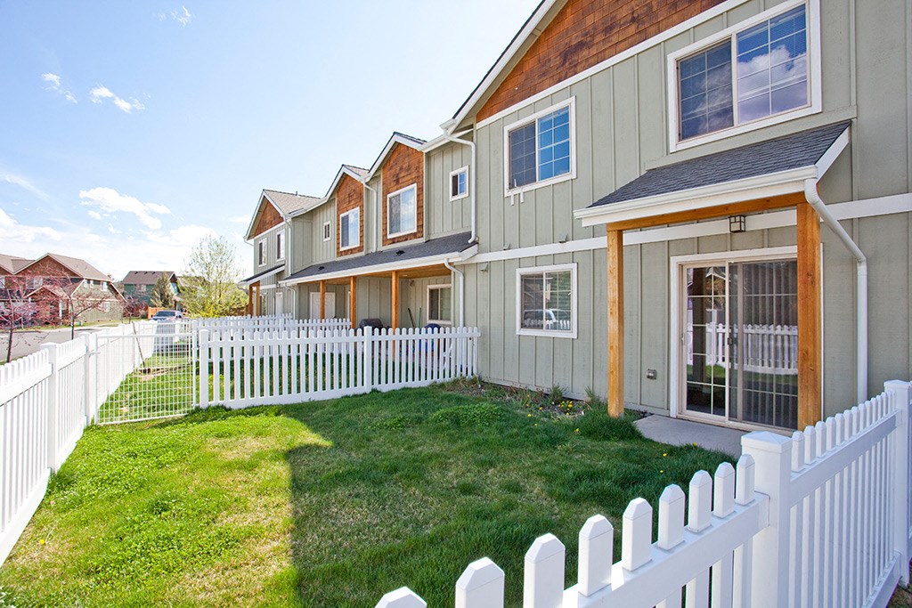 a row of houses with a yard and a white fence