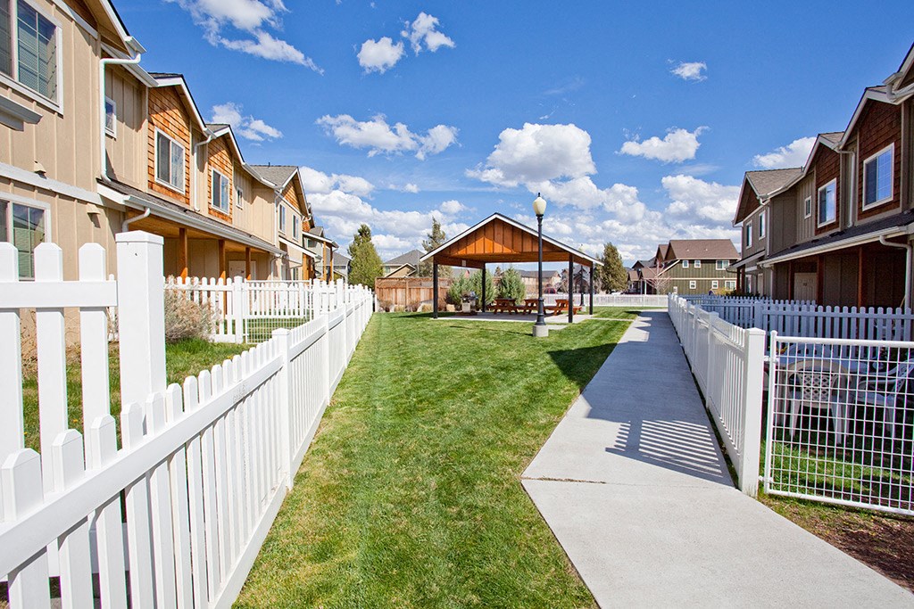 a yard with a white fence and houses on the side