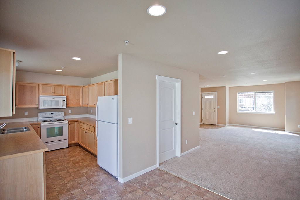 an empty kitchen with wooden cabinets and a white refrigerator