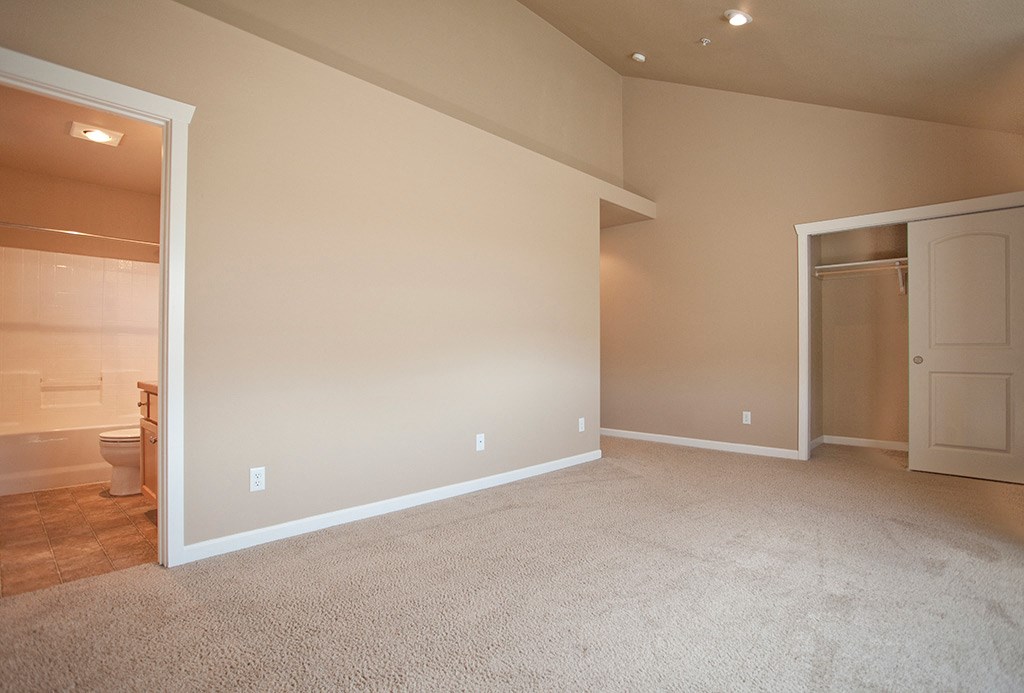 an empty living room with a bathroom and a toilet
