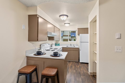 A kitchen with a white counter top and brown stools.
