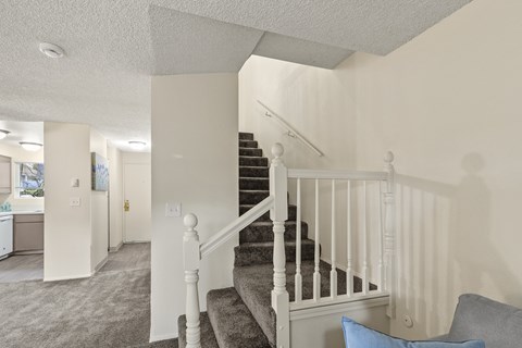 A staircase with a white railing and a grey carpet.