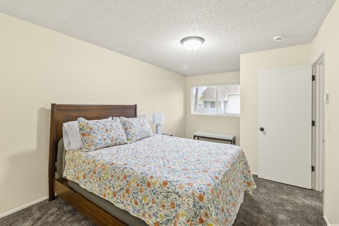 A bedroom with a bed, nightstand, and window.