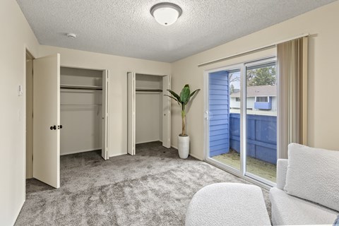 A room with a white couch, a potted plant, and a sliding glass door.